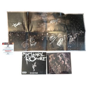 May include: An autographed My Chemical Romance poster and two CDs are displayed. The poster is folded and features band member signatures. The album covers are black and white, with the band's name and album title visible. A certificate of authenticity is also present.