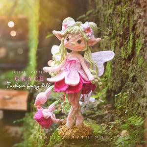 May include: A crocheted fuchsia fairy doll with a pink and white dress, green hair, and white wings. The doll has a flower crown and is standing on a mossy surface. The text "CROCHET PATTERN GRACE Fuchsia fairy doll" is visible.