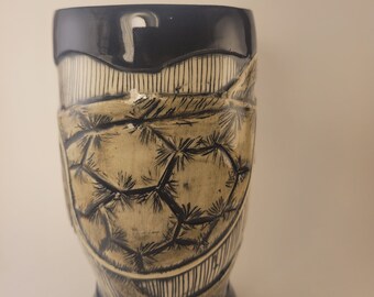 May include: A ceramic mug with a black rim and base. The mug has a white background with a black and white geometric design.