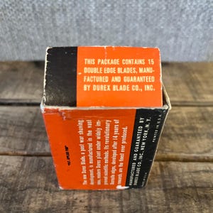 May include: A vintage box of Durex double edge blades. The box is orange and black with text that reads "This package contains 15 double edge blades, manufactured and guaranteed by Durex Blade Co., Inc."
