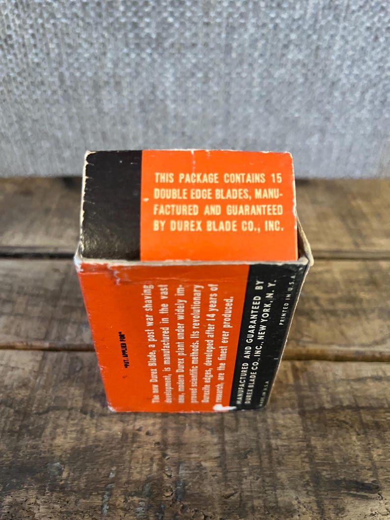 May include: A vintage box of Durex double edge blades. The box is orange and black with text that reads "This package contains 15 double edge blades, manufactured and guaranteed by Durex Blade Co., Inc."