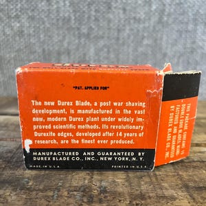 May include: Vintage orange and black Durex Blade box. The box features text that reads "PAT. APPLIED FOR" and details about the blade's manufacturing and features. The box is printed in the U.S.A.