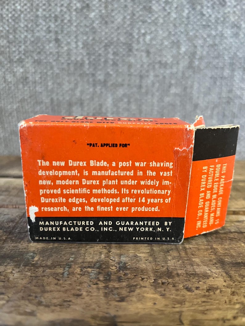May include: Vintage orange and black Durex Blade box. The box features text that reads "PAT. APPLIED FOR" and details about the blade's manufacturing and features. The box is printed in the U.S.A.