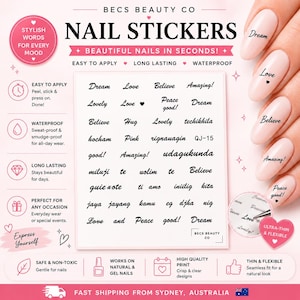 May include: A sheet of black nail stickers by Becs Beauty Co featuring various words like Dream, Love, and Believe in cursive script. The sheet includes multiple rows of text designs, and the image shows these stickers applied to light pink fingernails.