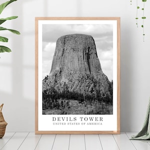 May include: Black and white photograph of Devils Tower National Monument in Wyoming, United States. The image shows the iconic rock formation, a large, cylindrical rock spire, rising from a grassy plain. The text "Devils Tower, United States of America" is printed below the image.