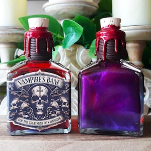 May include: Two glass bottles with cork stoppers and labels. The bottle on the left is filled with a red liquid and has a label that reads "Vampire's Bane For the Treatment of Vampirism". The bottle on the right is filled with a purple liquid.