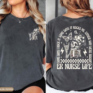 May include: Pepper-colored t-shirt featuring a skeleton in a nurse's cap with the text "ER NURSE LIFE." The back of the shirt has a larger graphic with butterflies and the phrase "Some days I rock it, some days it rocks me. Either way we're rockin'."