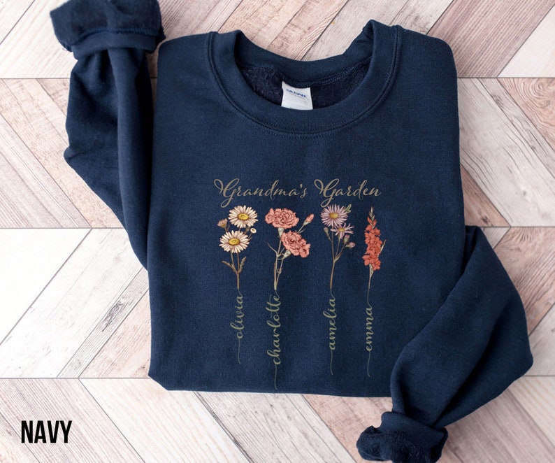 May include: Navy blue sweatshirt with a floral design and the text "Grandma's Garden". The names Olivia, Charlotte, Amelia, and Emma are written vertically below the flowers.