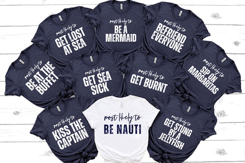 Op de afbeelding: Negen marineblauwe T-shirts met witte tekst, elk met een andere grappige zin over een vakantie. De zinnen zijn: "Most likely to be at the buffet", "Most likely to get lost at sea", "Most likely to be a mermaid", "Most likely to befriend everyone", "Most likely to get sea sick", "Most likely to get burnt", "Most likely to sip on margaritas", "Most likely to kiss the captain", "Most likely to get stung by a jellyfish". Een wit T-shirt met marineblauwe tekst zegt "Most likely to be nauti".