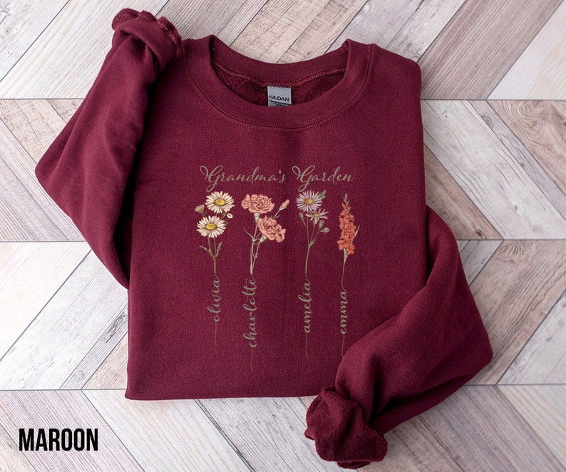 May include: Maroon sweatshirt with the text "Grandma's Garden" and a floral design. The names Olivia, Charlotte, Amelia, and Emma are written below the flowers.