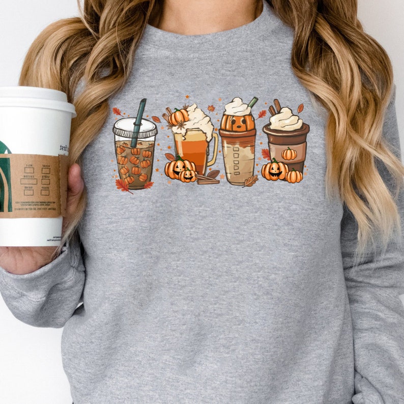 May include: Gray sweatshirt with a graphic of four fall-themed drinks with pumpkin spice and fall leaves. The drinks include a pumpkin spice latte, a pumpkin spice iced coffee, a pumpkin spice milkshake, and a pumpkin spice hot chocolate.