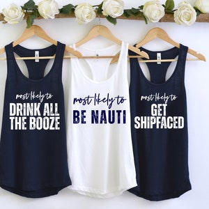 Op de afbeelding: Drie marineblauwe tanktops met witte tekst. De tekst op de tops luidt "most likely to drink all the booze", "most likely to be nauti" en "most likely to get shipfaced".