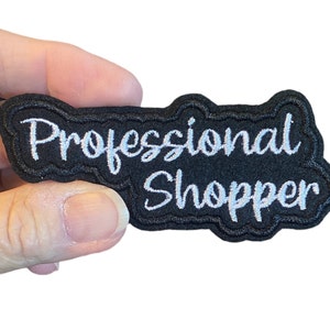 May include: Black embroidered patch with white text that reads "Professional Shopper".