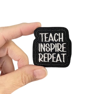 May include: Black iron-on patch with white embroidered text that reads "Teach Inspire Repeat".
