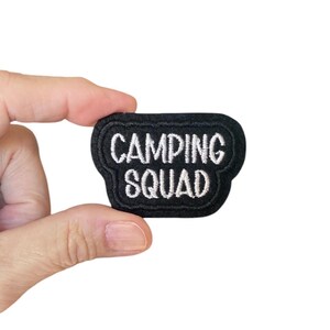 May include: Black felt patch with white embroidered text that reads "Camping Squad".