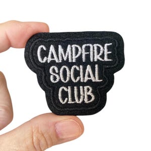 May include: Black embroidered patch with white text that reads "Campfire Social Club".