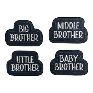 May include: Four black embroidered patches with white text. The patches read "BIG BROTHER", "MIDDLE BROTHER", "LITTLE BROTHER", and "BABY BROTHER". The patches have a rounded rectangular shape.