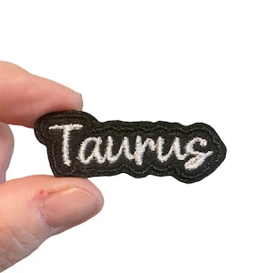 May include: Black embroidered patch with white lettering that reads "Taurus".