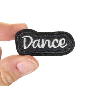 May include: Black fabric patch with white embroidered text that reads "Dance".