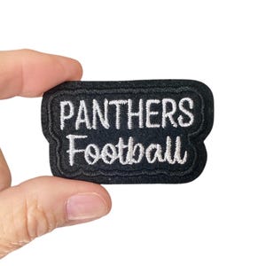 May include: Black felt patch with white embroidered text that reads "Panthers Football".