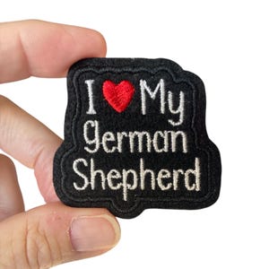 May include: Black embroidered patch with white text that reads "I love my German Shepherd" with a red heart in the middle.