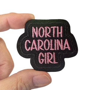 May include: Black embroidered patch with pink lettering that reads "North Carolina Girl".