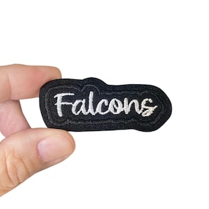 May include: Black fabric patch with white embroidered text that reads "Falcons".