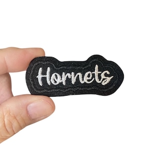 May include: Black felt patch with white embroidered text that reads "Hornets".