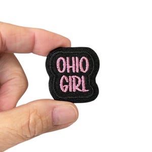 Puede incluir: Parche de tela negro con texto bordado en rosa que dice "Ohio Girl".