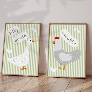 Peut inclure: Deux affiches encadrées avec des animaux de dessins animés. L'une montre une oie blanche avec le texte "silly goose" sur un fond à rayures vertes. L'autre montre une poule grise avec le texte "cocotte".