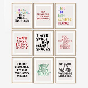 May include: Nine framed art prints with humorous quotes in various colors. The quotes include phrases like "Daydreaming is a full-time job" and "I need space - and maybe snacks." The prints are in a gallery wall arrangement.