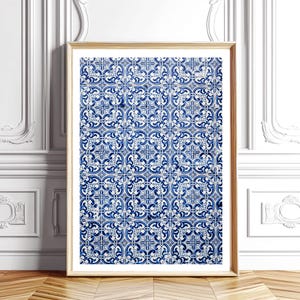 Puede incluir: Una impresión enmarcada que presenta un patrón repetitivo de azulejos decorativos azules y blancos. Los azulejos tienen un diseño floral y geométrico. El marco es de color madera clara, y la impresión está apoyada contra una pared blanca con molduras decorativas.