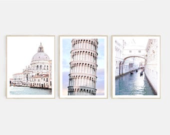May include: Three framed prints of Venice, Italy. The first print shows a white building with a dome, the second print shows a white tower, and the third print shows a canal with a bridge.