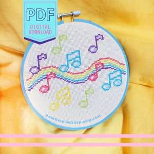 May include: A digital PDF download pattern for a cross stitch design featuring a rainbow with musical notes. The pattern is for a round embroidery hoop.