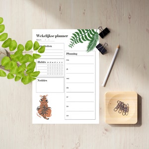 May include: A printable weekly planner with a tropical leaf design. The planner includes sections for daily tasks, habits, and notes. A tiger illustration is at the bottom of the page.