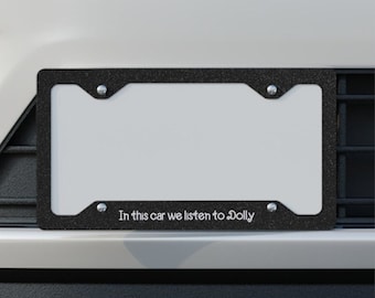 May include: Black license plate frame with silver screws and the text "In this car we listen to Dolly".