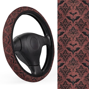 May include: A black steering wheel with a decorative cover featuring a dark red damask pattern with black bat silhouettes. The cover adds a spooky, gothic touch to the car's interior. The design is repeated on a separate fabric panel.
