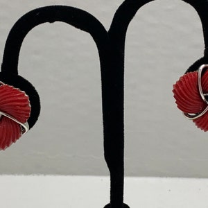May include: A pair of red and silver clip-on earrings. The earrings are shaped like a flower with a silver wire design.