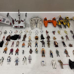 以下が含まれることがあります： Xウィング、戦闘機、さまざまなキャラクターなど、スターウォーズのアクションフィギュアと宇宙船のコレクション。フィギュアはさまざまなポーズと衣装で、さまざまな色とデザインがあります。宇宙船は白、オレンジ、黄色です。