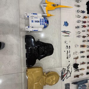 以下が含まれることがあります： スターウォーズのおもちゃのコレクション。黄色と銀色のスターファイター、白と青のR2-D2フィギュア、黒のダース・ベイダーヘルメット、金色のC-3POフィギュアが含まれています。さまざまなアクションフィギュアとアクセサリーも含まれています。