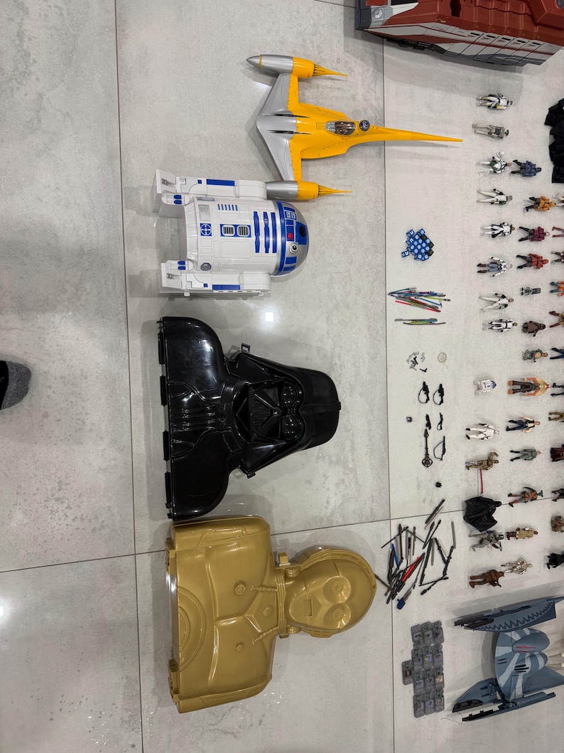 以下が含まれることがあります： スターウォーズのおもちゃのコレクション。黄色と銀色のスターファイター、白と青のR2-D2フィギュア、黒のダース・ベイダーヘルメット、金色のC-3POフィギュアが含まれています。さまざまなアクションフィギュアとアクセサリーも含まれています。