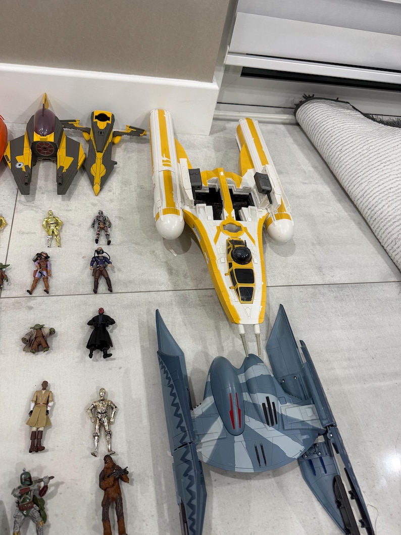 以下が含まれることがあります： スターウォーズのおもちゃのコレクション。宇宙船とアクションフィギュアが含まれています。宇宙船は主に黄色、グレー、白で、詳細なデザインが施されています。アクションフィギュアは、スターウォーズの世界のさまざまなキャラクターを表しています。