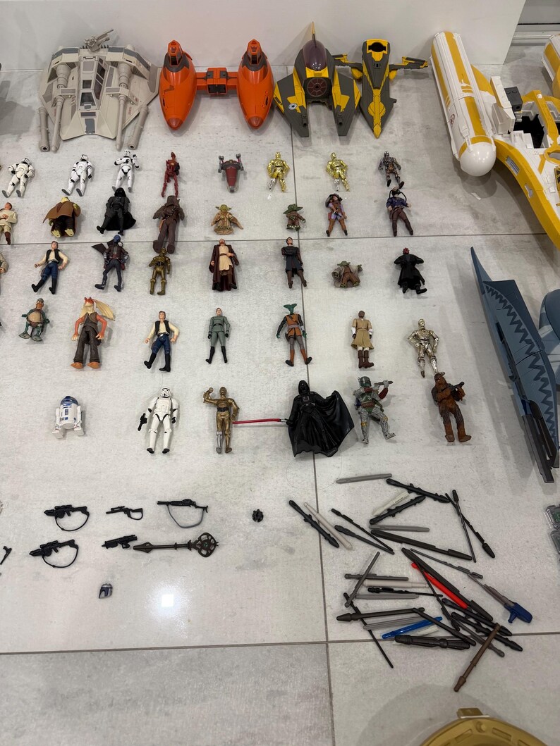 以下が含まれることがあります： スターウォーズのアクションフィギュアと乗り物のコレクション。Xウィング、戦闘機、ダース・ベイダー、ストームトルーパー、ヨーダなどの様々なキャラクターが含まれています。おもちゃは様々なサイズと色で、明るい色の表面に配置されています。