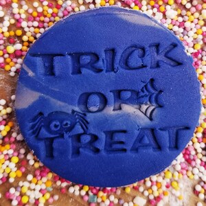 May include: A blue round cookie cutter with the words "Trick or Treat" and a spider design.