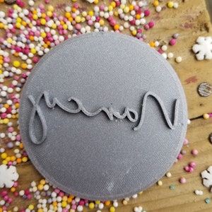 May include: A gray round cookie cutter with the word "Grandma" written in cursive.