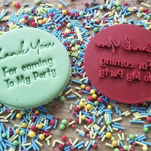 May include: Two round, green and red cookie cutters with the text "Thank You For coming To My Party" on them. The cutters are surrounded by colorful sprinkles.