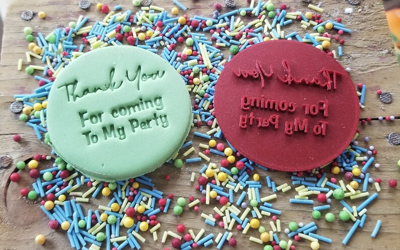 May include: Two round, green and red cookie cutters with the text "Thank You For coming To My Party" on them. The cutters are surrounded by colorful sprinkles.