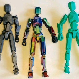 May include: Three articulated action figures in gray, multicolored, and green. The figures are humanoid in shape, with jointed limbs and heads. The multicolored figure has a rainbow of colors throughout its body. The figures are standing upright.