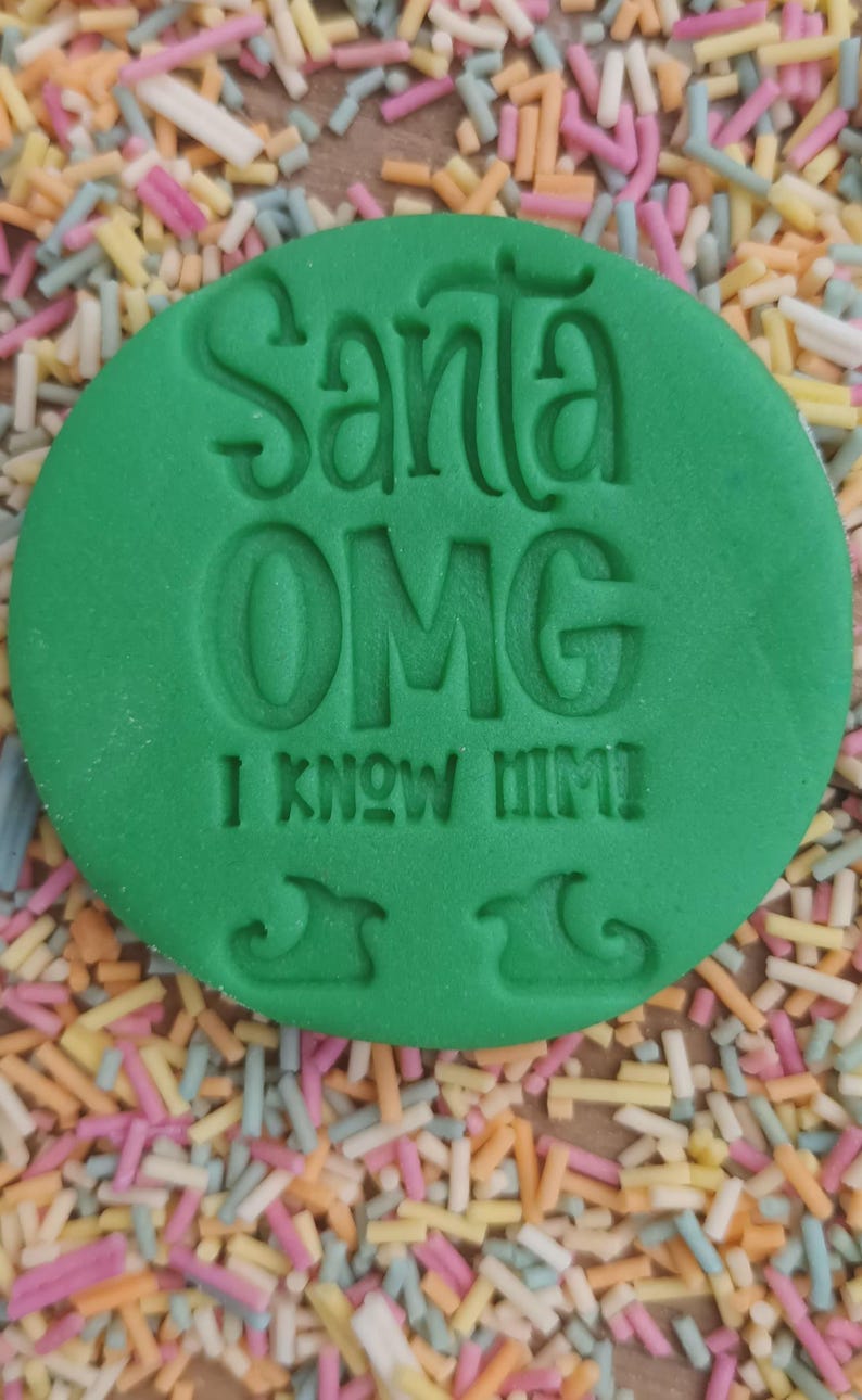 K&ouml;nnte beinhalten: Gr&uuml;ner runder Ausstecher mit dem Text "Santa OMG I know him!" und zwei Umrissen von Elfen-Schuhen.