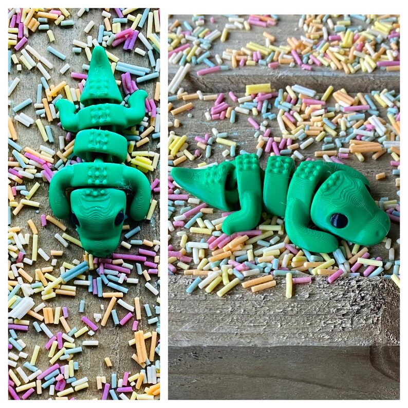 May include: A green articulated alligator toy on a background of colorful sprinkles.